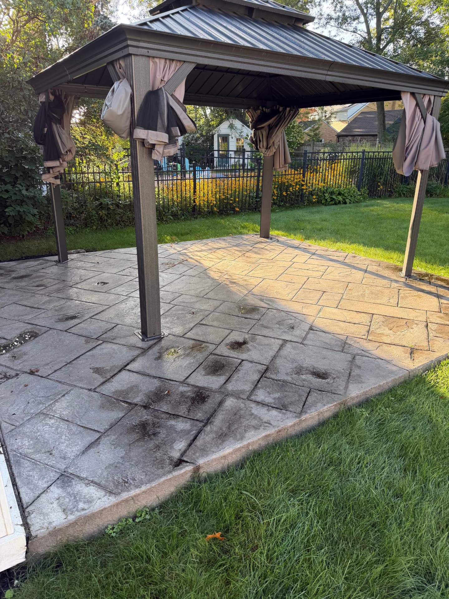 Before — stamped concrete patio under a gazebo washed, re-colored and sealed